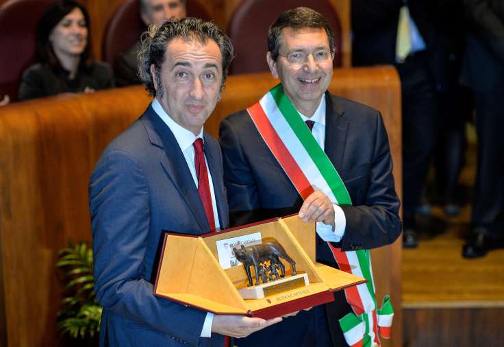 Oscar award winner for best Foreign film "The great beauty", Italian director Paolo Sorrentino (L) poses with an honorary trophy, a statue of the wolf, symbol of Rome, next to the Mayor of Rome Ignazio Marino during the ceremony of conferment of honorary citizenship, on March 14, 2014 at the Campidoglio in Rome. AFP PHOTO / ANDREAS SOLARO