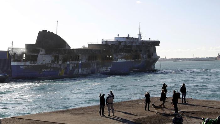 The Norman Atlantic ferry is being towed into the port of Brindisi, southern Italy, Friday, Jan. 2, 2015. The blaze that broke out Sunday and torched the ferry has killed at least 11 people and authorities prepared to search it for possible more dead. Italy says 477 people were rescued, most by helicopters that plucked survivors off the top deck in gale-force winds and carried them to nearby boats. (AP Photo/Antonio Calanni) [Credit: ANSA]