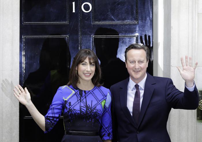 Britain's Prime Minister David Cameron and his wife Samantha wave from the steps of 10 Downing Street in London Friday, May 8, 2015 after meeting Britain's Queen Elizabeth II where he informed her  that he has enough support to form a government.  The Conservative Party swept to power Friday in Britain's Parliamentary elections winning an unexpected majority.  (ANSA/AP Photo/Alastair Grant )